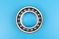 Single ball bearing close up, isolated on blue background with copy space on the sides.