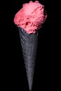 Single ball of strawberry ice cream in a black ice cream waffle isolated on black background Royalty Free Stock Photo