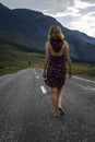 Single barefoot woman is walking along the mountain road. Travel, tourism and people concept Royalty Free Stock Photo