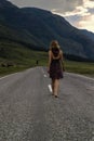 Single barefoot woman is walking along the mountain road. Travel, tourism and people concept Royalty Free Stock Photo