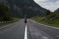 Single barefoot woman is walking along the mountain road. Travel, tourism and people concept Royalty Free Stock Photo