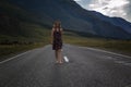 Single barefoot woman is walking along the mountain road. Travel, tourism and people concept Royalty Free Stock Photo