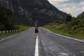 Single barefoot woman is walking along the mountain road. Travel, tourism and people concept Royalty Free Stock Photo