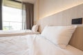 2 single beds with white bedding are in the cream bedroom of hotel that turn on the headboard light and open the gray curtain Royalty Free Stock Photo