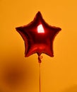 Single big red star balloon ballon object for birthday party on yellow Royalty Free Stock Photo