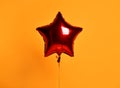 Single big red star metallic balloon ballon object for birthday party on orange Royalty Free Stock Photo