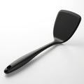 A black matte spatula with a long handle and a hole at the end, isolated on a white background Royalty Free Stock Photo