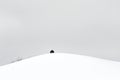 A Single Black Object on a Snowy Hilltop Under a Cloudy Sky Royalty Free Stock Photo