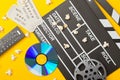 Single, black, open movie clapper or clapper-board with dvd movie disc, film reel, popcorn, remote control and movie theatre Royalty Free Stock Photo