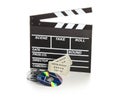 Single, black, open movie clapper or clapper-board with dvd movie disc, film reel and movie theatre tickets on white - digital Royalty Free Stock Photo