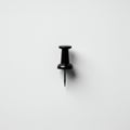 A single black pushpin is embedded into a flat, white surface. The pushpin features a Royalty Free Stock Photo