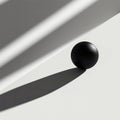 A single black sphere sits in light and shadow on a white surface. Royalty Free Stock Photo