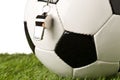 Single black and white soccer sports ball with referee whistle close up with selective focus on green grass over white