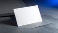 Single blank white business card angled on a dark textured surface with blue light mockup Royalty Free Stock Photo