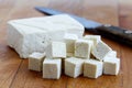 Single block of white tofu with cut tofu cubes and rustic knife