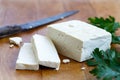 Single block of white tofu with two tofu slices, crumbs, fresh p