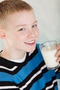 Single blond boy with glass of milk near mouth