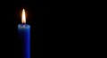 Single blue candle burning with a bright flame isolated on a black background with copy space Royalty Free Stock Photo
