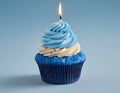 Single blue Cupcake With a Burning Candle on blue Background Royalty Free Stock Photo