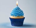 Single blue Cupcake With a Burning Candle on blue Background Royalty Free Stock Photo