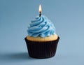 Single blue Cupcake With a Burning Candle on blue Background Royalty Free Stock Photo