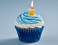 Single blue Cupcake With a Burning Candle on blue Background Royalty Free Stock Photo