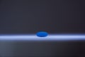 Single blue pill illuminated by a single sharp beam