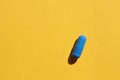 Single blue pill on a yellow paper background. Top view, copy space. Medicine capsule on colored backdrop Royalty Free Stock Photo