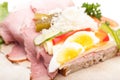 A bread topped with smoked meat, eggs, vegetables and cheese