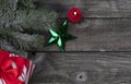 Single bright green star ornament and burning candle, gift box plus snow fir branch decorations on rustic wooden planks for a Royalty Free Stock Photo