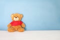 Single brown bear doll wear red shirt sit on white bed on blue background wall in bedroom look fresh like someone out it to surpri Royalty Free Stock Photo