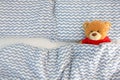 Single brown bear doll wear red shirt sleeping on the bed have space on the left side. Concept waiting for someone to sleep with h