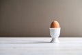 Single brown chicken egg in a ceramic egg cup on a light wooden table with copy space. Royalty Free Stock Photo