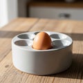 A single brown egg rests in a white ceramic egg holder with multiple compartments. Royalty Free Stock Photo