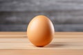 A single brown eggshell rests upright on a wooden table against a blurred gray background Royalty Free Stock Photo