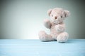 Single brown teddy bear furry setting on a blue wooden table on the green background behind Royalty Free Stock Photo