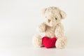 Single brown teddy bear with red heart yarn.
