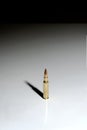 A single bullet 7.62 x 51 mm NATO standing on a white surface with a black background Royalty Free Stock Photo