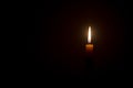 Single small yellow candle light glowing isolated on black or dark background on table in church or temple for Christmas, funeral Royalty Free Stock Photo