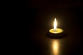 A single burning candle flame or light glowing on small green candle on black or dark background on table in church Royalty Free Stock Photo