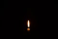 Single burning candle flame or light glowing on a small white candle on black or dark background on table in church for Christmas Royalty Free Stock Photo