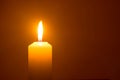 A single burning candle flame or light glowing on a yellow candl Royalty Free Stock Photo