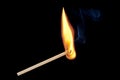 A single burning match with flames and smoke rising up, isolated on a black background Royalty Free Stock Photo