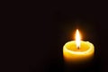 Single Burning Yellow Candle Glowing on a Dark Background. Copy Space Royalty Free Stock Photo