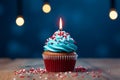 Single candle atop a blue cupcake with vibrant red sprinkles Royalty Free Stock Photo