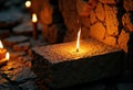 Illuminated candle flame flickers on a stone surface in a warm, rustic setting Royalty Free Stock Photo