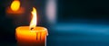 Single candle glowing softly in the dark, its flame casting a warm light. A minimal night-themed background with ample Royalty Free Stock Photo