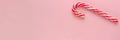 Single candy cane on pink background. Banner. Candy Cane Day concept. Sweet Christmas symbol. Top view. Copy space