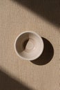 Minimalist Ceramic Bowl with Shadow on Earth-Toned Linen Surface Royalty Free Stock Photo