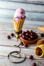 A single cherry ice cream cone in a metal spiral stand with a bowl of cherries in behind. Royalty Free Stock Photo